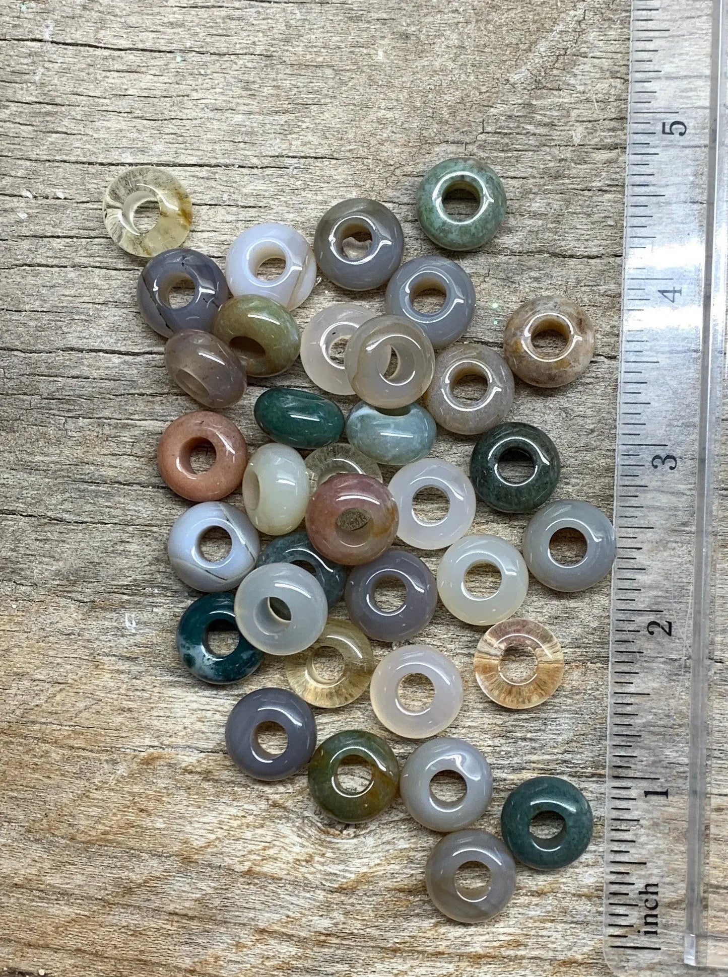 "Close-up view of polished 14mm agate beads with vibrant patterns and colors, positioned next to a ruler