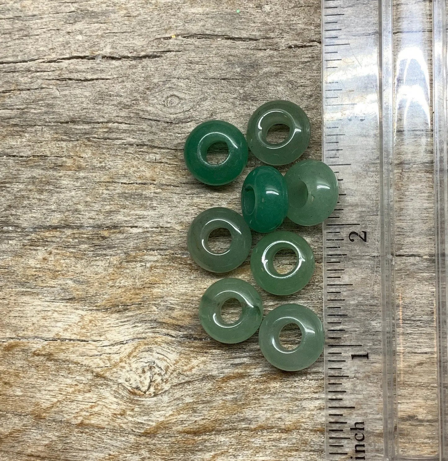 "Close-up of 14mm round green Aventurine beads, showing their smooth surface and rich color next to a ruler