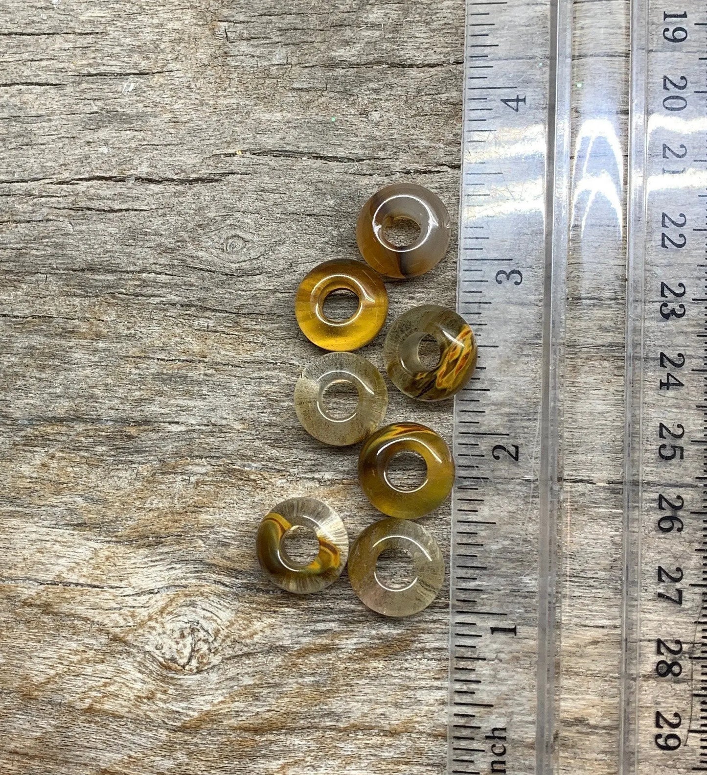 "Close-up of 14mm green tourmaline beads, showcasing their vibrant color and smooth texture, next to a ruler
