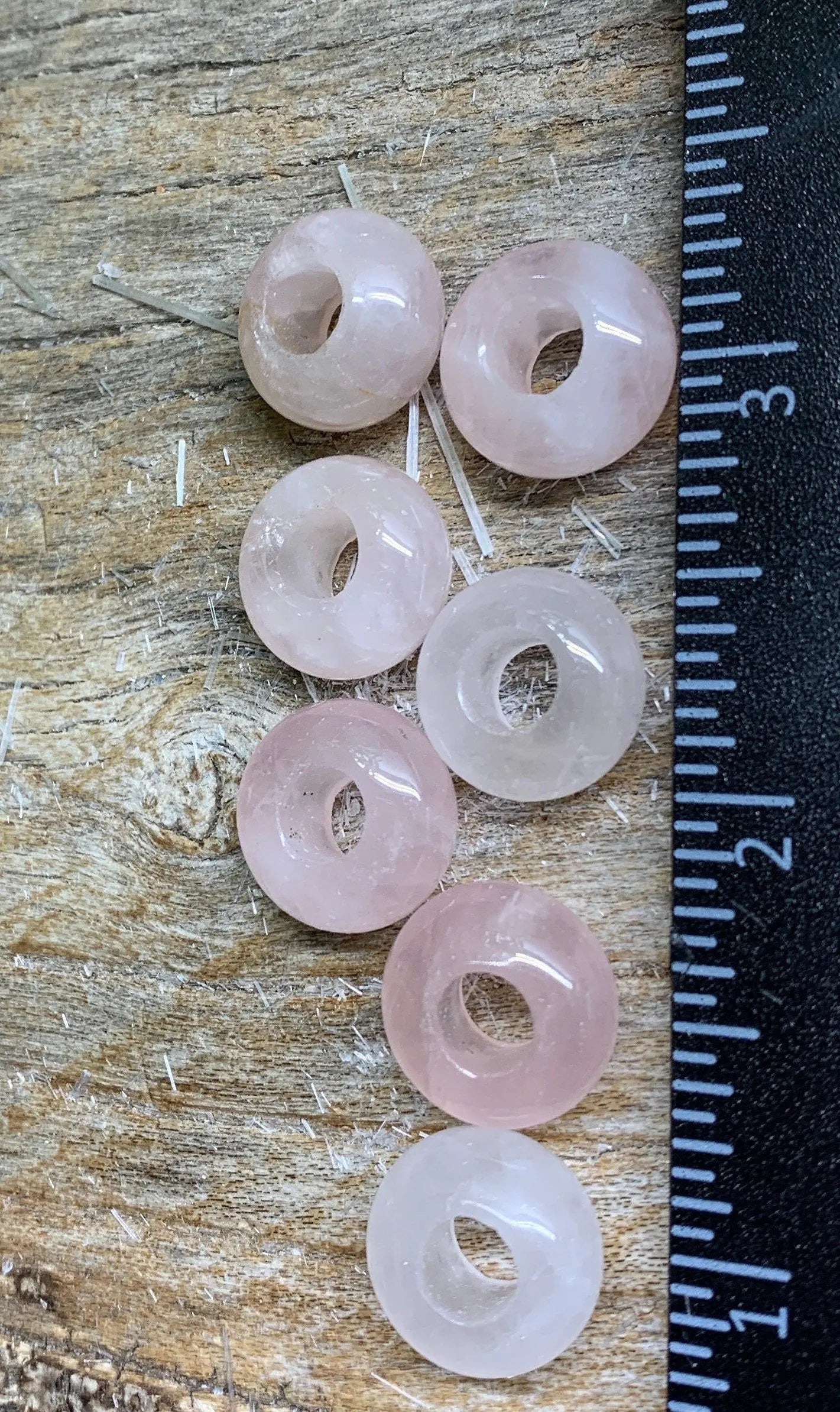 Close up pf 14mm rose quartz beads: Smooth, round beads in soft pink color, ideal for jewelry crafting and design near a ruler to show size