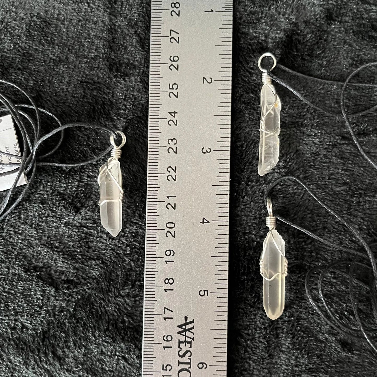 3 Silver wire wrapped dazzling lemunian quartz point pendants attarched to adjustable black cords, displayed next to a ruler. Stone is approximately 1" - 1 1/4" long.