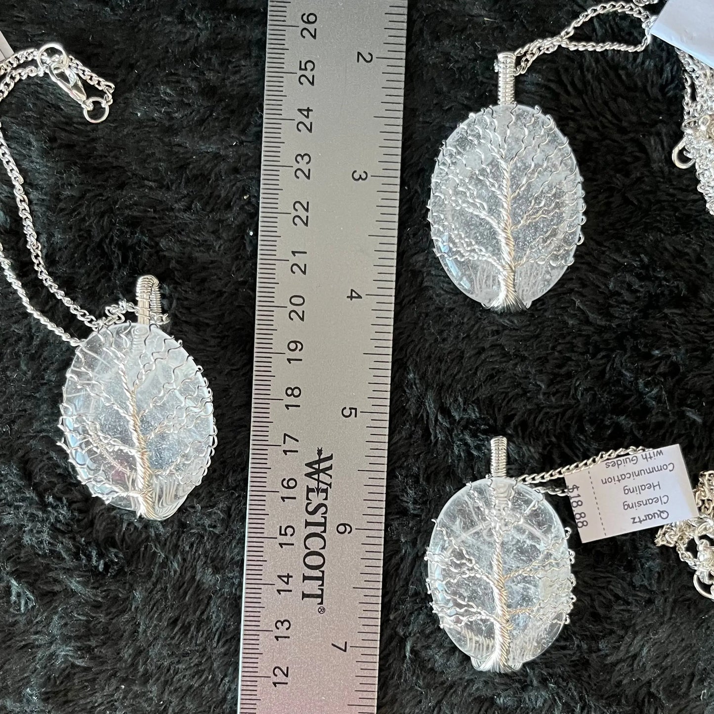 Fancy wrap, tree of life wire wrapped dazzling clear wuartz oval pendant attatched to a silver chain displayed next to a ruler. pendant is approximately 2 inched long