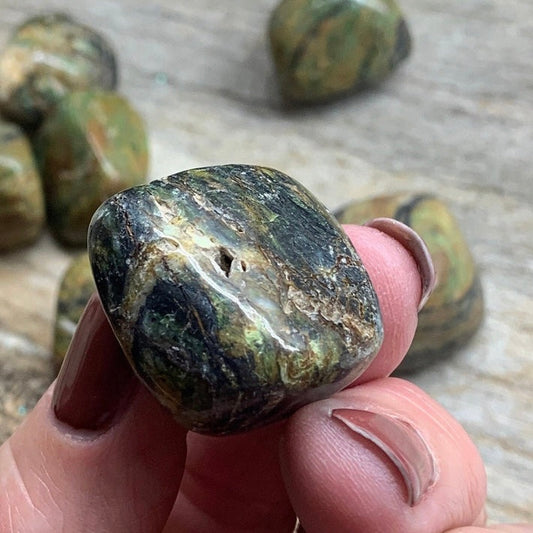 “Alt text: A close-up image of African turquoise gemstones showcasing vibrant blue-green hues with brown and black matrix patterns. The stones are smooth, round, and reflective, highlighting their natural beauty and unique texture.