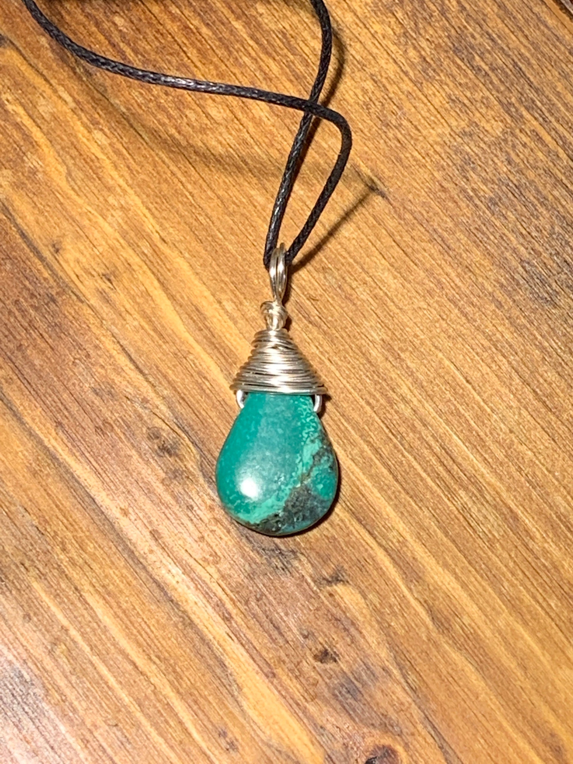 solver wire wrapped authentic turquoise cabochon tear drop pendant, approximately 1" long, attatched to an adjistable black cord