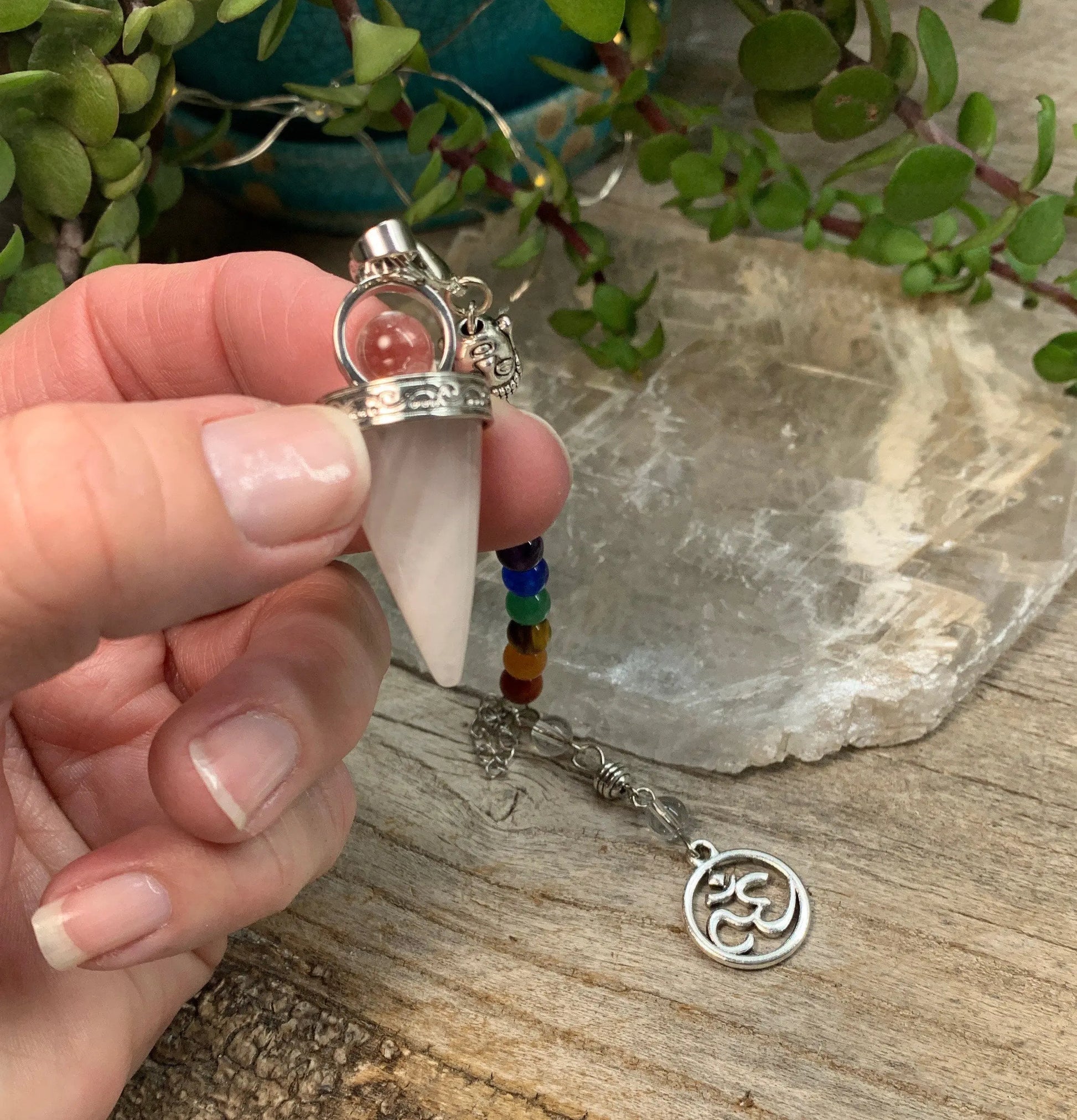 1 inch amethyst pendulum attatched to 8 inch chain including a silver crescent moon held delicately in 3 fingertips