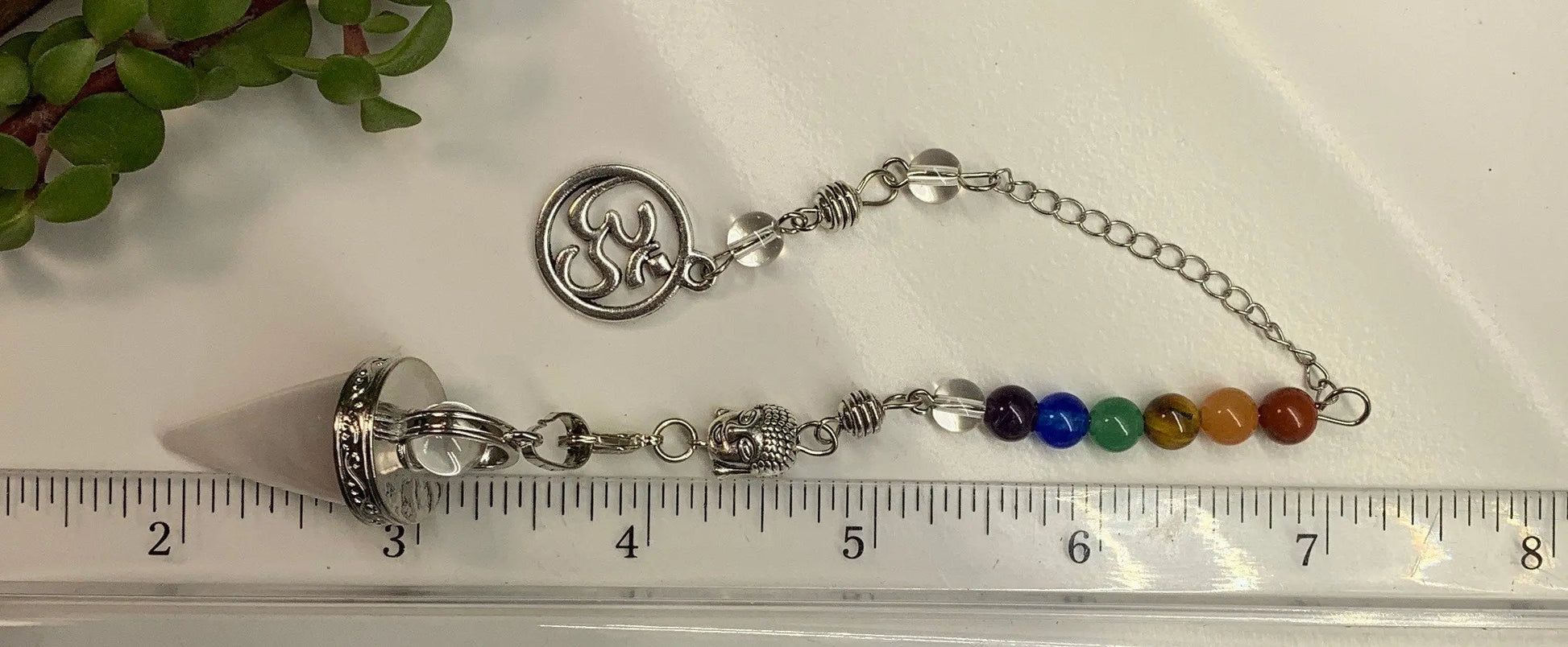 1 inch amethyst pendulum attatched to 8 inch chain including a silver crescent moon displayed next to a ruler