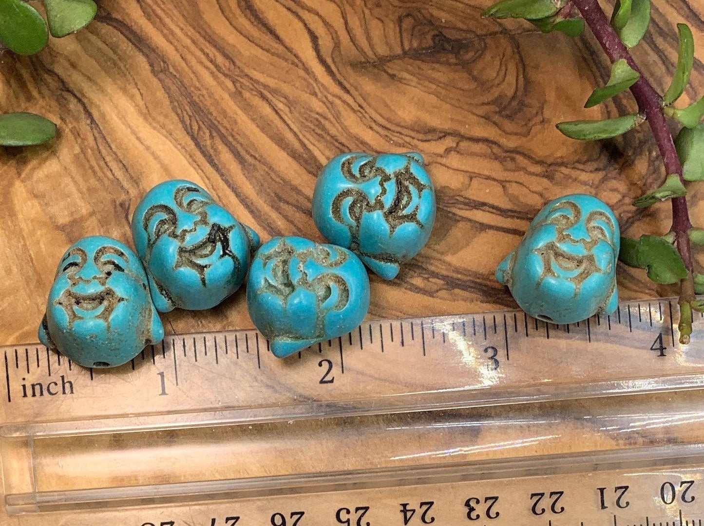 "Close-up image of a 3/4-inch blue Howlite Happy Buddha head, showcasing its intricate details and vibrant blue color, positioned next to a ruler to show size