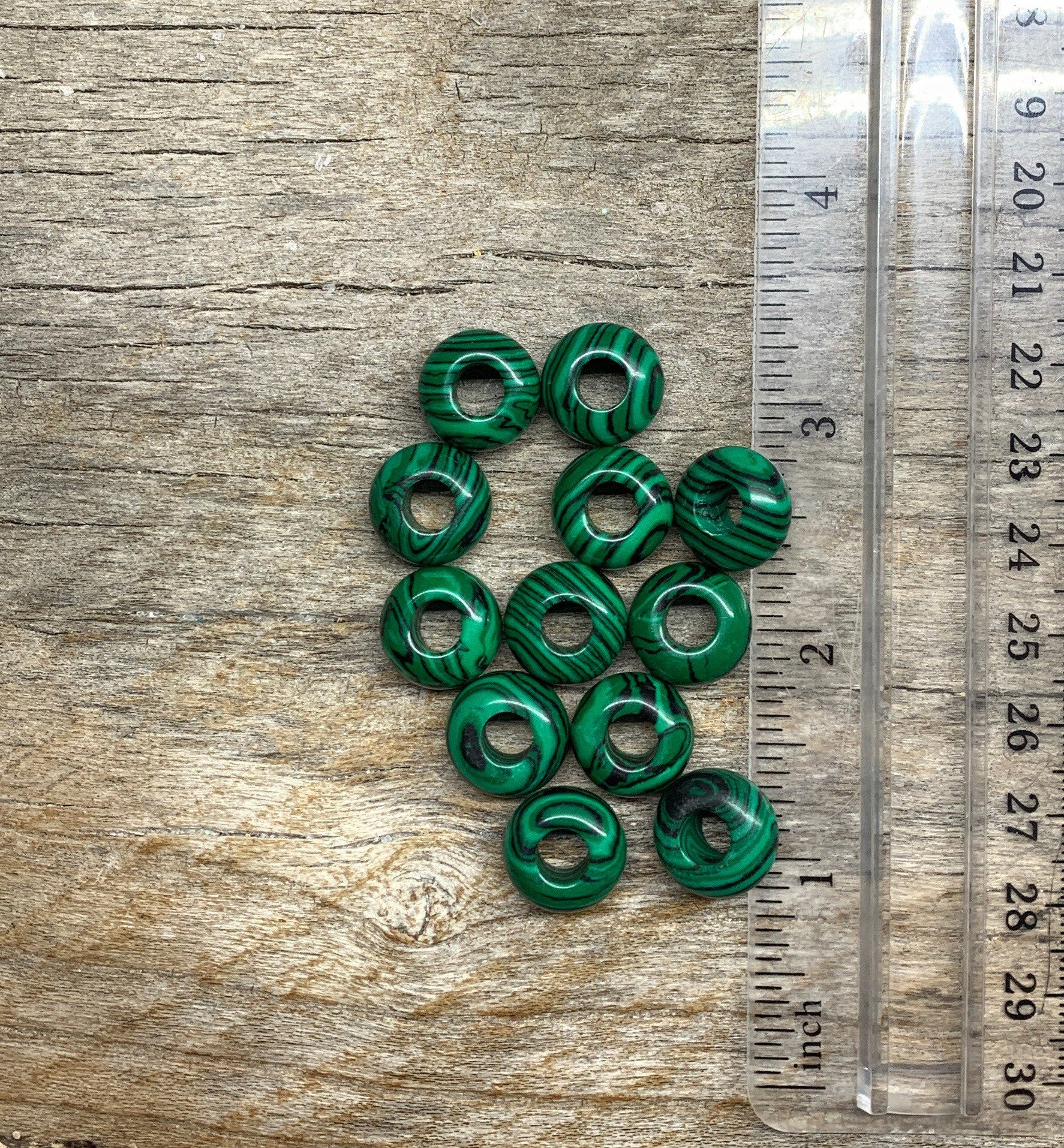 “Close-up of vibrant green malachite beads with unique striated patterns, creating an eye-catching accessory next to a ruler to show size