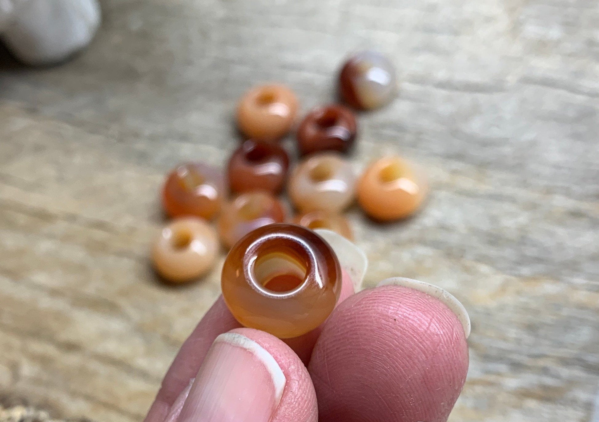 Close-up view of 14mm carnelian agate beads, showcasing their vibrant orange hues and smooth, polished surfaces