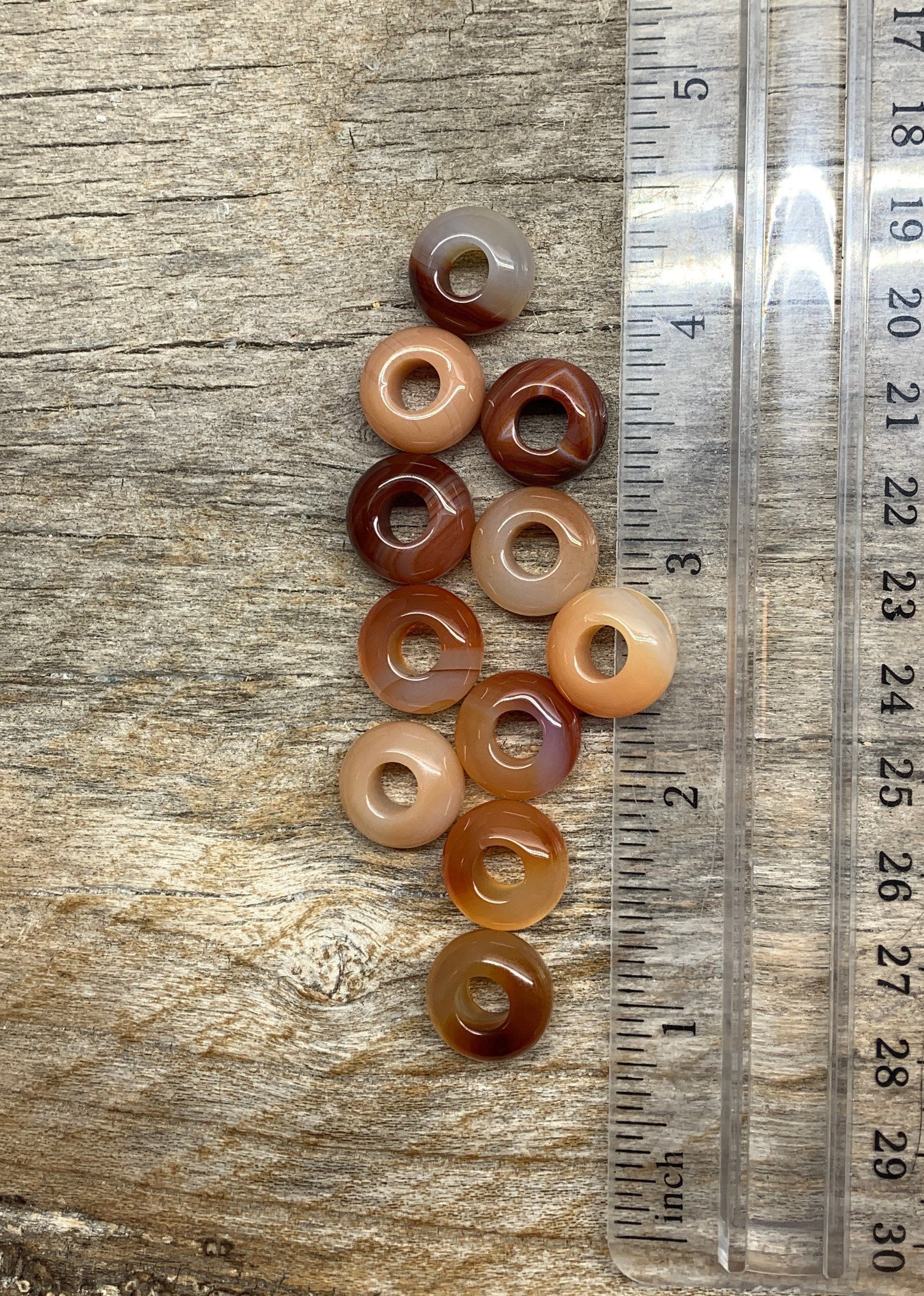 Close-up view of 14mm carnelian agate beads, showcasing their vibrant orange hues and smooth, polished surfaces next to a ruler