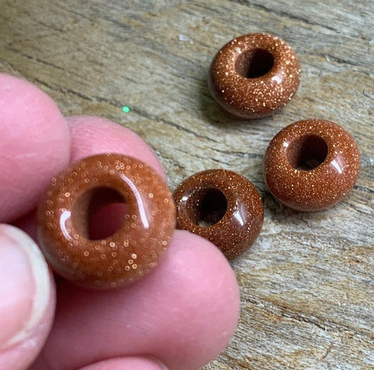 "Close-up view of 14mm goldstone beads, featuring sparkling coppery flecks against a dark background.