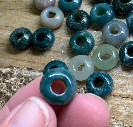 "Close-up view of lustrous moss agate beads, showcasing intricate green and brown patterns."