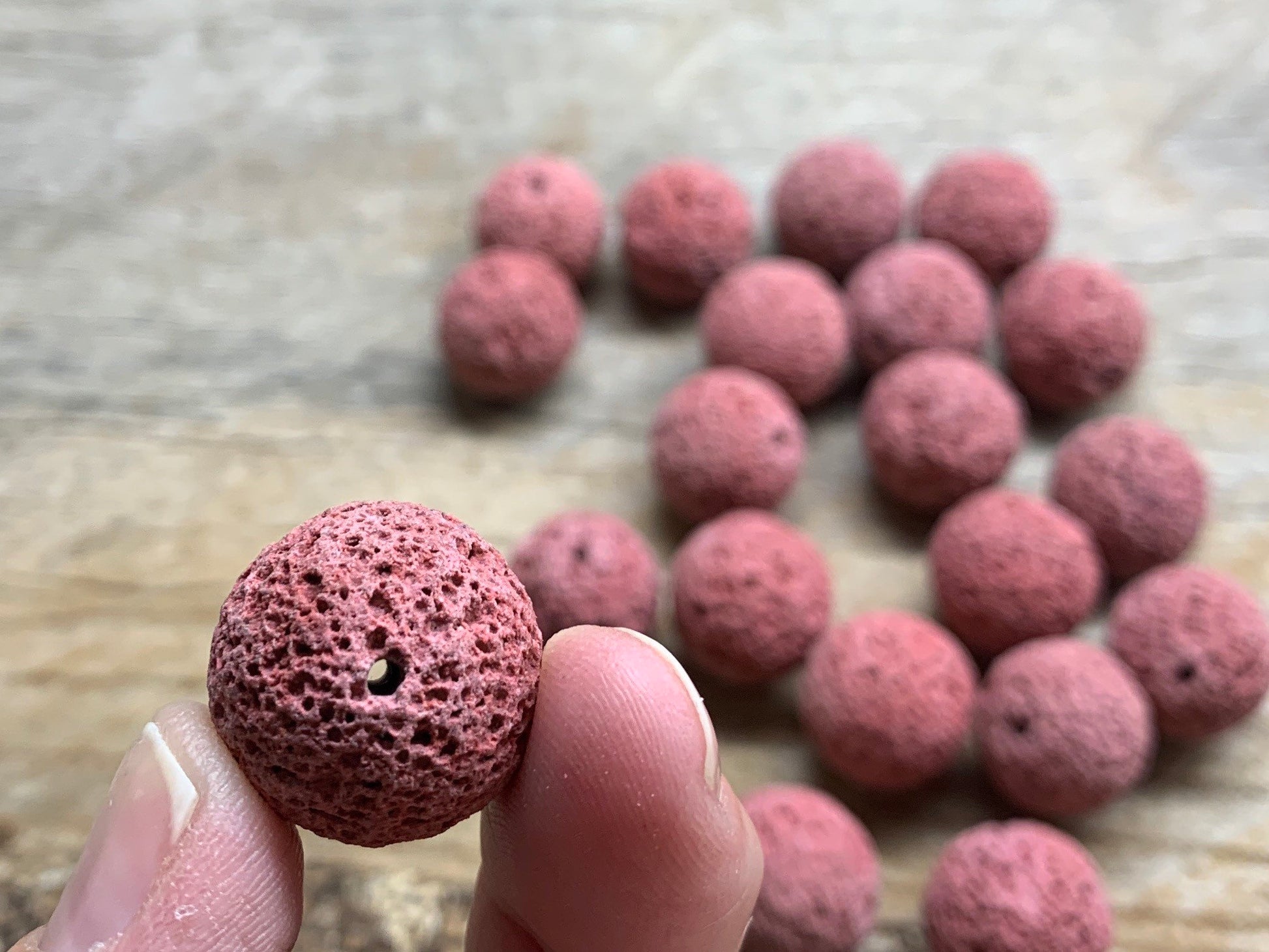  vibrant pink lava beads, formed through volcanic processes, showcasing a unique porous texture.