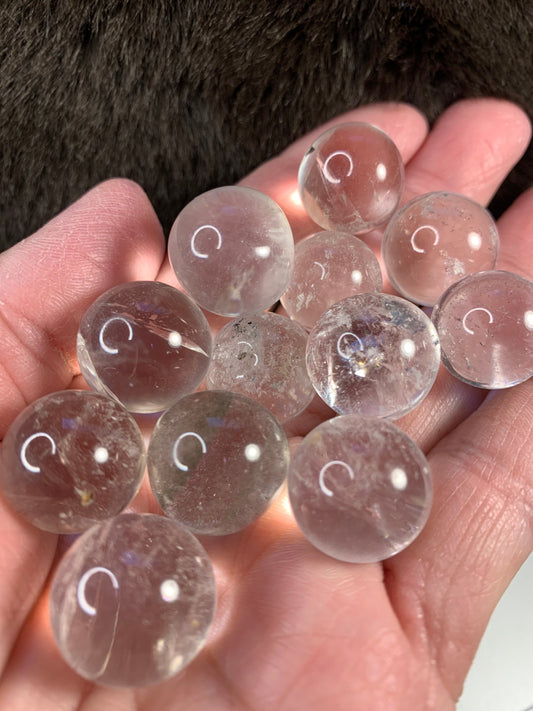 a handful of shiny polished clear quartz spheres approximately 1/2" - 5/8" in diameter