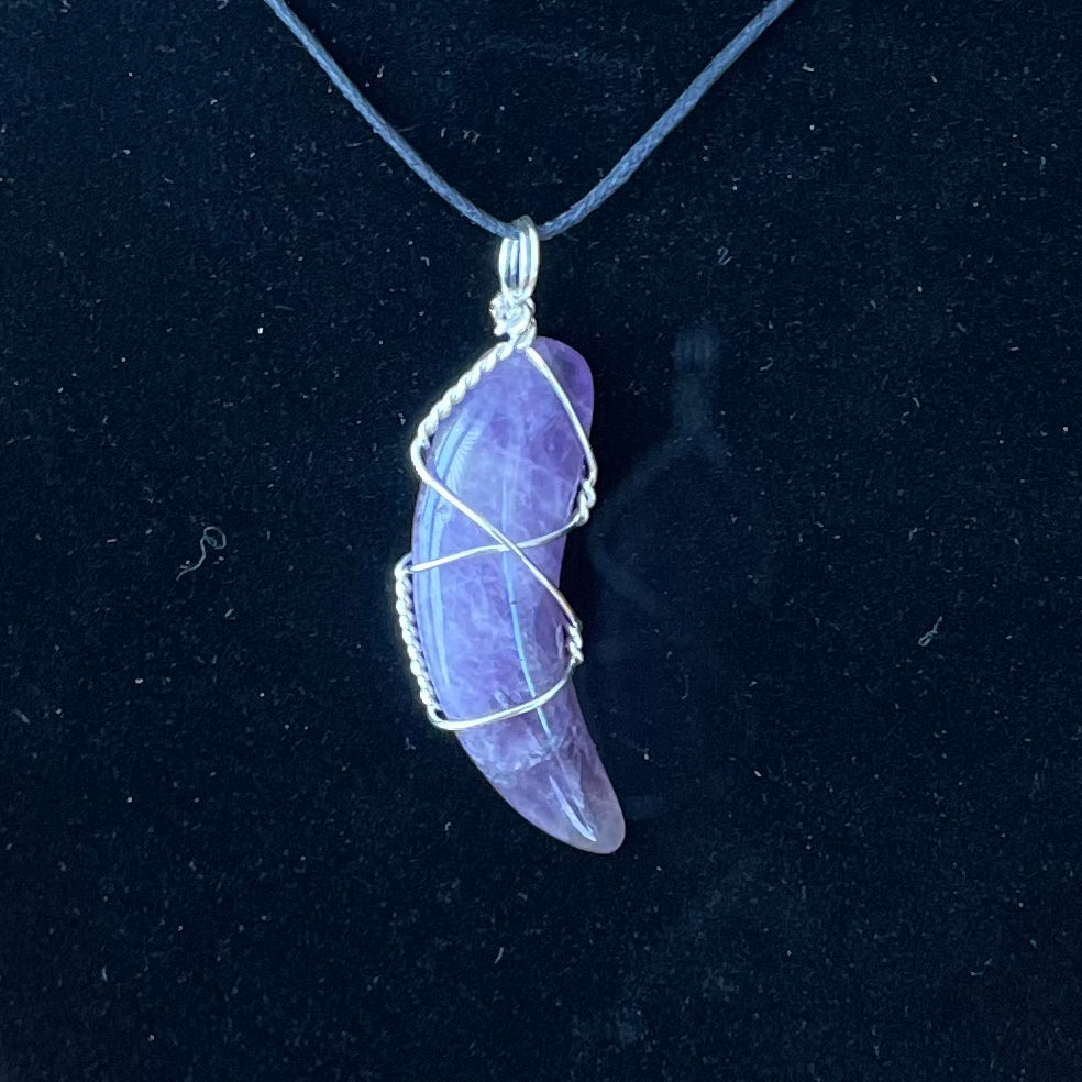 amethyst crescent moon, silver wire wrapped pendant attatched to a black adjustable cord displayed against a black background to enhance the beautiful purple tone interlaced with white 