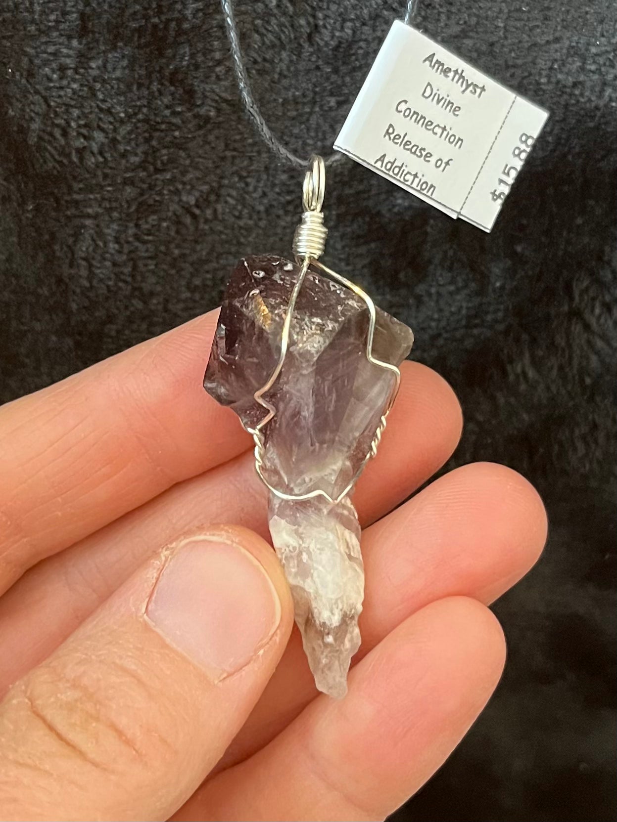 silver wire wrapped raw amethyst crystal pendant. attatched to an adjustable black cord.  It's transluscent purple near the top and  fades into white near the bottom.  approximately 1 1/2 inches long.  