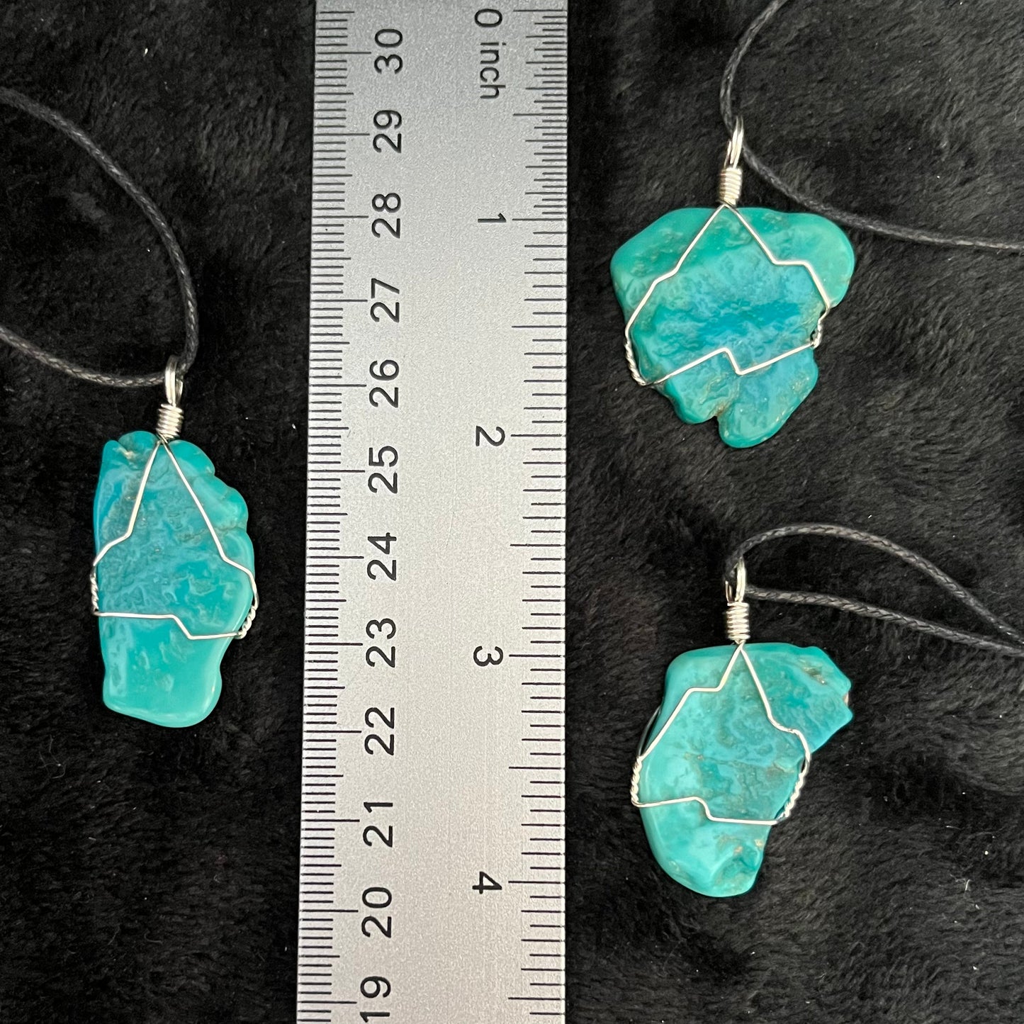 3 silver wire wrapped genuine sky blue turquoise pendant,  1" - 1 1/4" long, attatched to an adjistable black cords, displayed next to a ruler