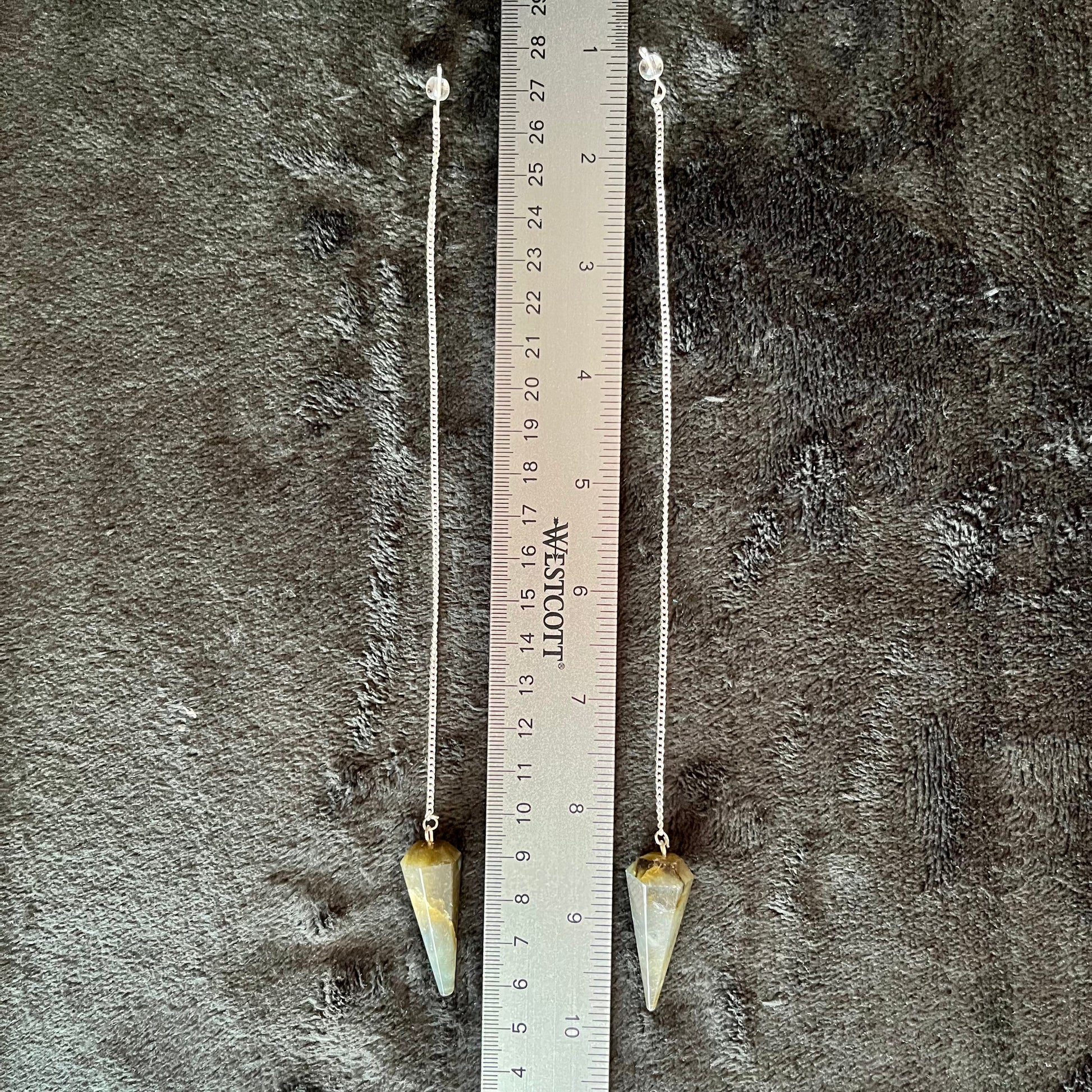 1 1/2 inch Labradorite crystal point pendulum attatched to an 8 inch silve chain, displayed next to a ruler to show size.