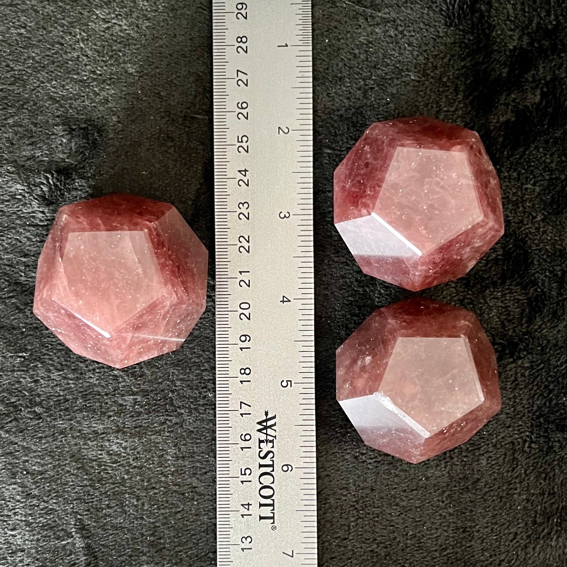 Three beautiful translucent pink strawberry quartz dodecahedrons display next to a ruler to show size. Each is approximately 45 mm in diameter.