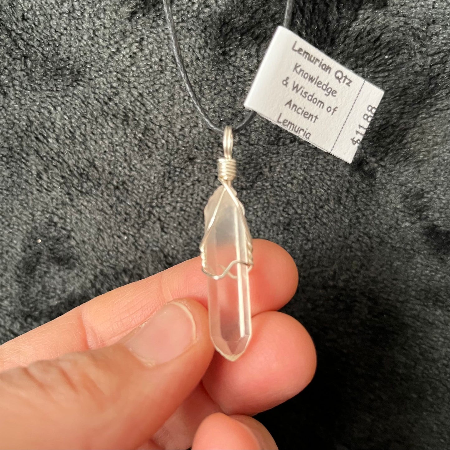 Silver wire wrapped dazzling lemunian quartz point pendant attarched to an adjustable black cord.  Stone is approximately 1" long.