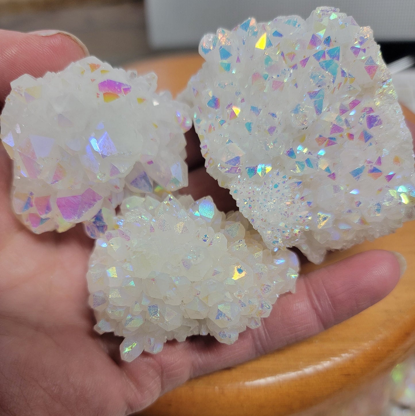 3 mesmerizing Angel Aura Quartz clusters featuring iridescent pastel hues, reflecting shades of pink, purple, and blue, with delicate crystal formations.  Each quartz cluster is 2”-3” long.