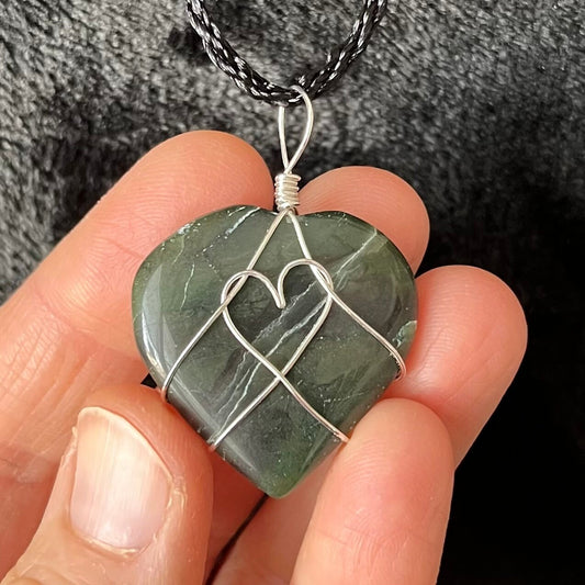 Silver wire wrapped, green jade heart pendant, approximately 3/4" X 1", attarched to an adjustable black cord.