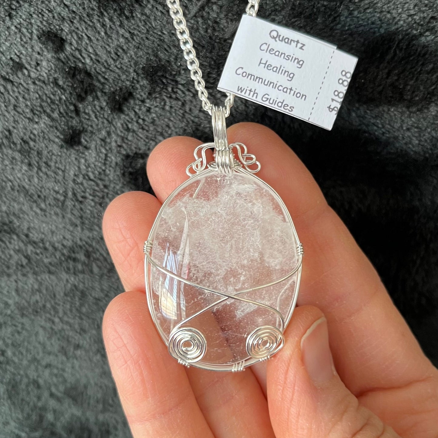 Silver fancy wire wrapped clear quartz oval stone pendant attatched to a silver chain.