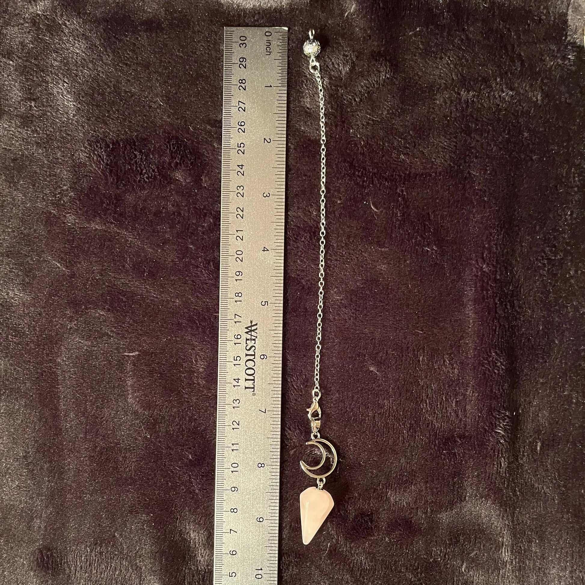1 inch rose quartz pendulum attatched to an 8 inch silver chain including a silver crescent moon next to a ruler