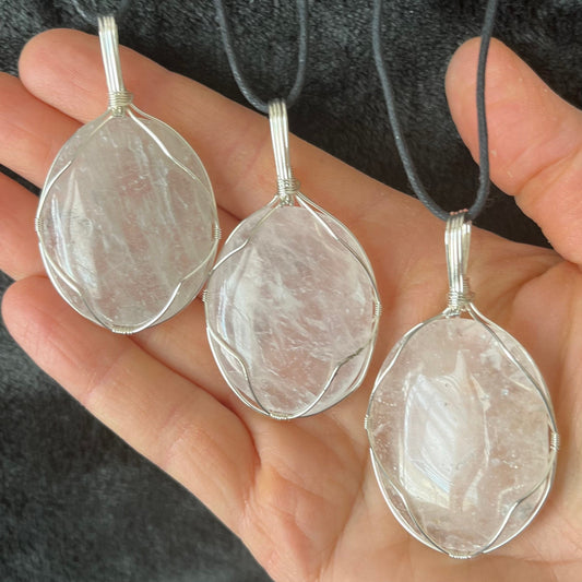 3 clear quartz worry stones beautifully silver wire wrapped in a way that frames the stone beautifully allowing access to the smoothe concave side on the back.  pe dants are approximately 2 inches long and attatched to adjustable black cords.