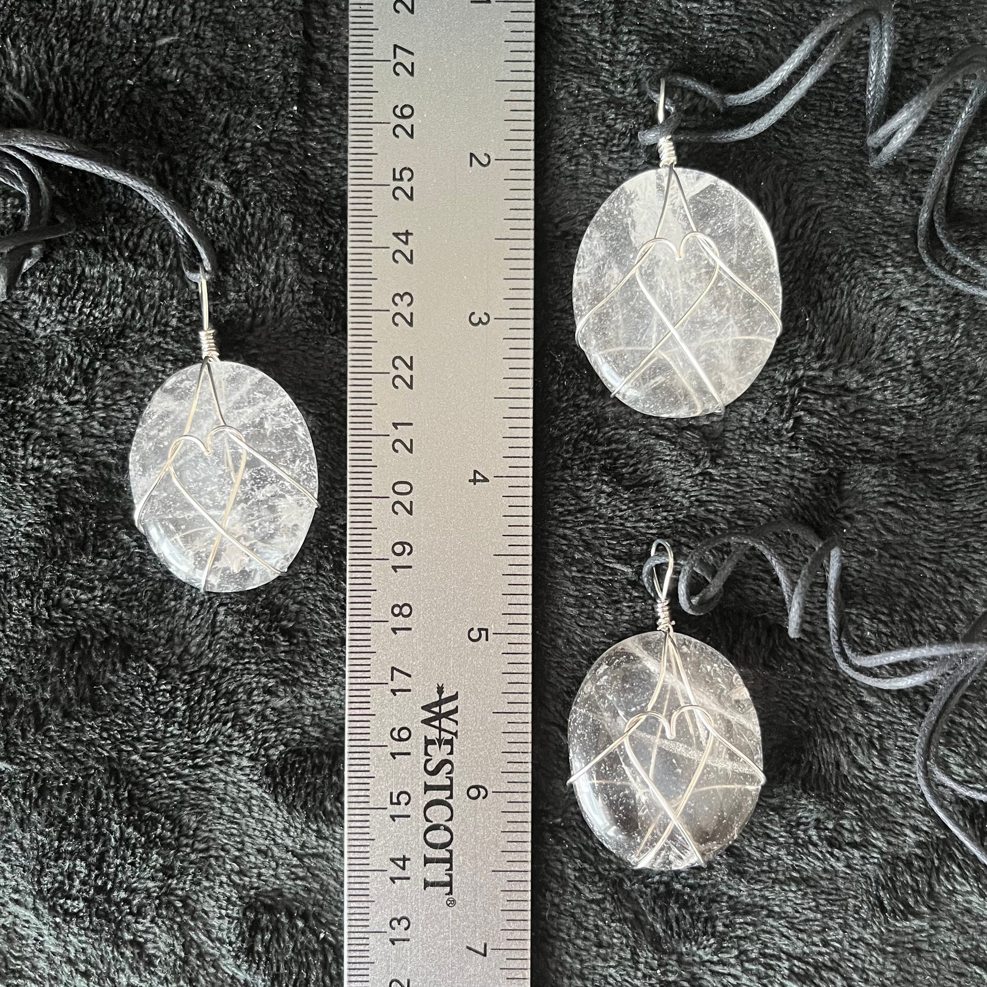 clear quartz worry stone beautifull silver wire wrapped to create a heart shape in the center.  pendant is attatched to an adjistable black cord and is approximately 1 3/4" long, displayed next to a ruler to show size