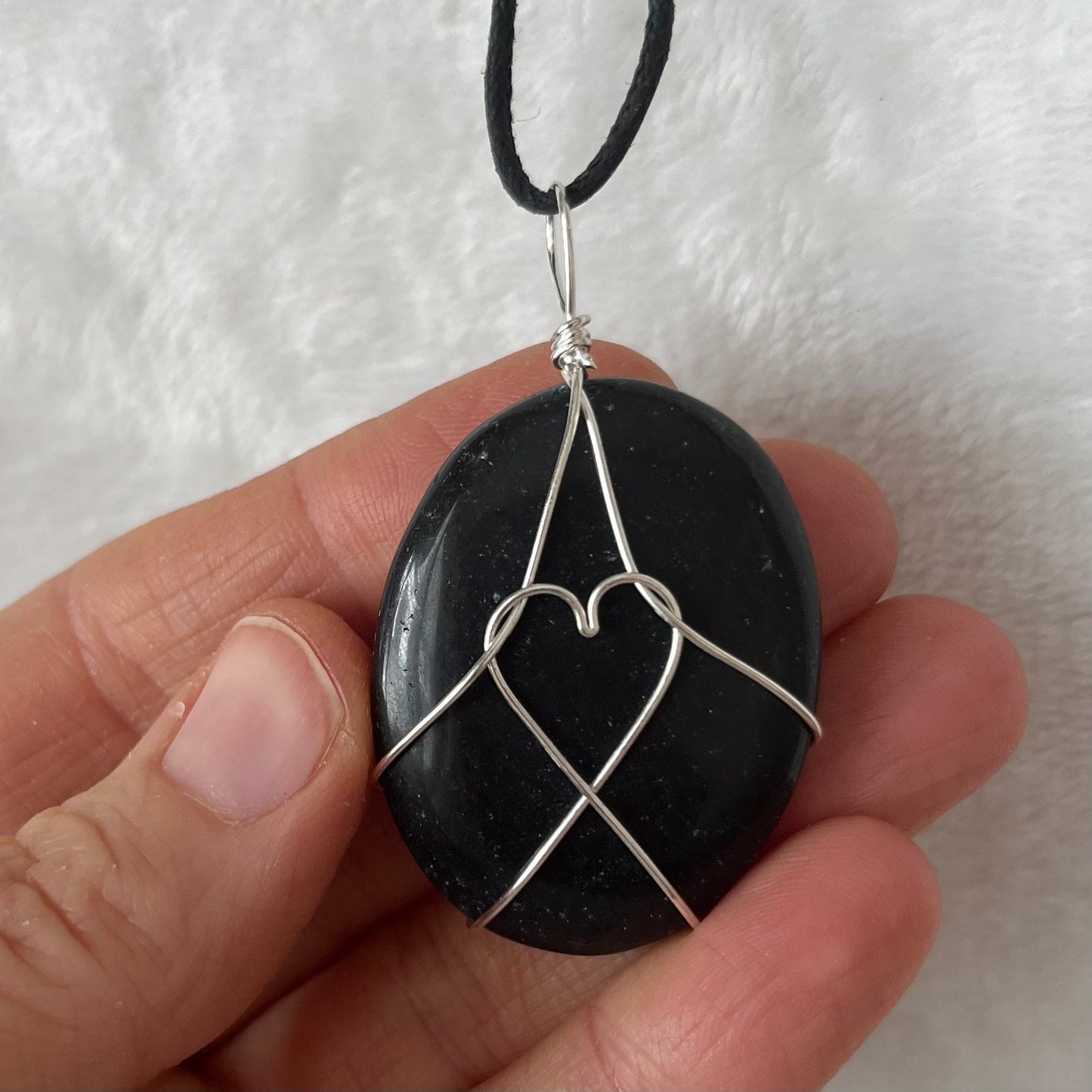 Silver wire wrapped obsidian worry stone pendant, with an adjiatable black cord.  obsidian crystal os approximately 1 1/2" long.  wire males a heart shape in the middle of the stone.