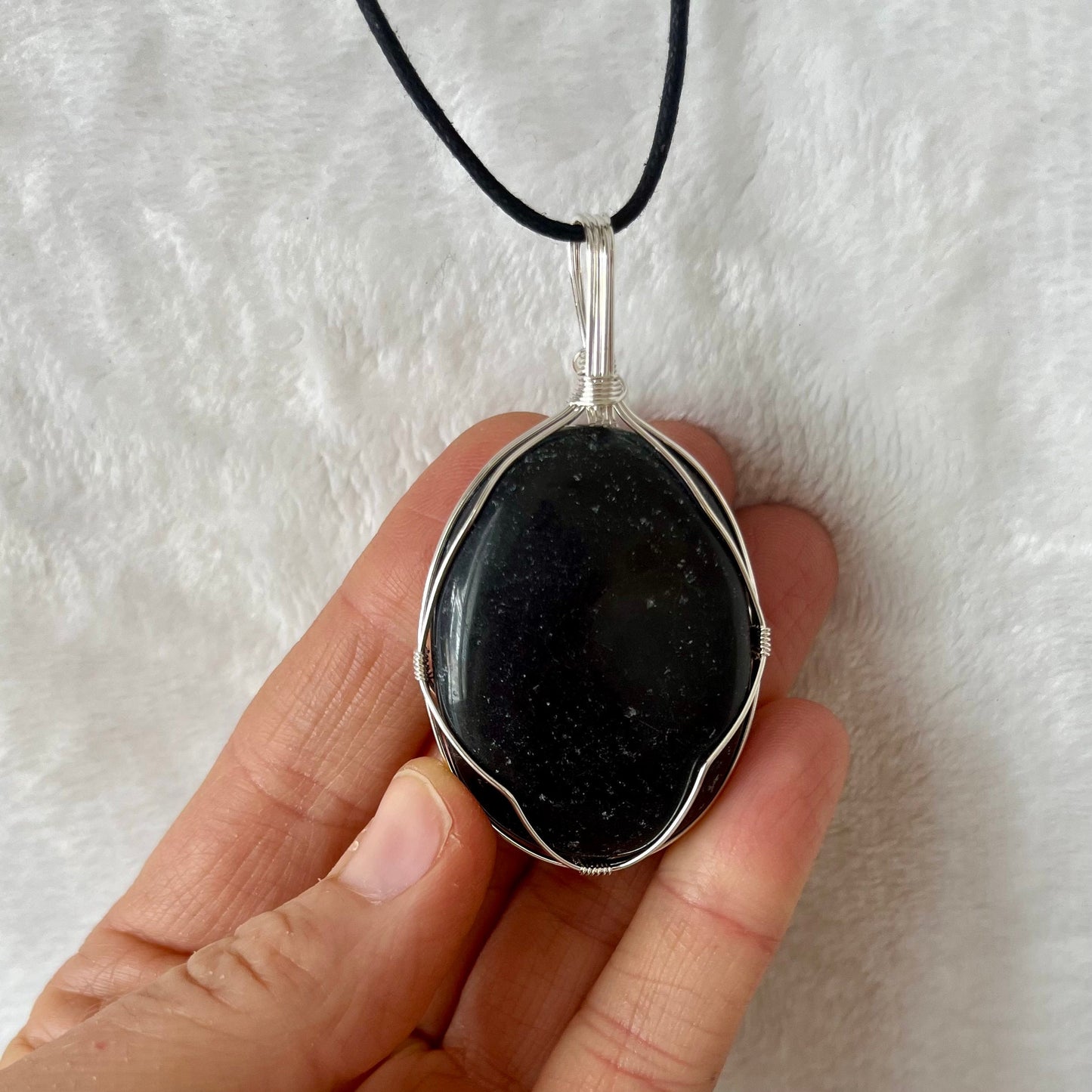 obsidian worry stone beautifully framed by silver wire and made into a pendant, with an adjustable black cord.  obsidian crystal worry stone s approximately 1 1/2" long.