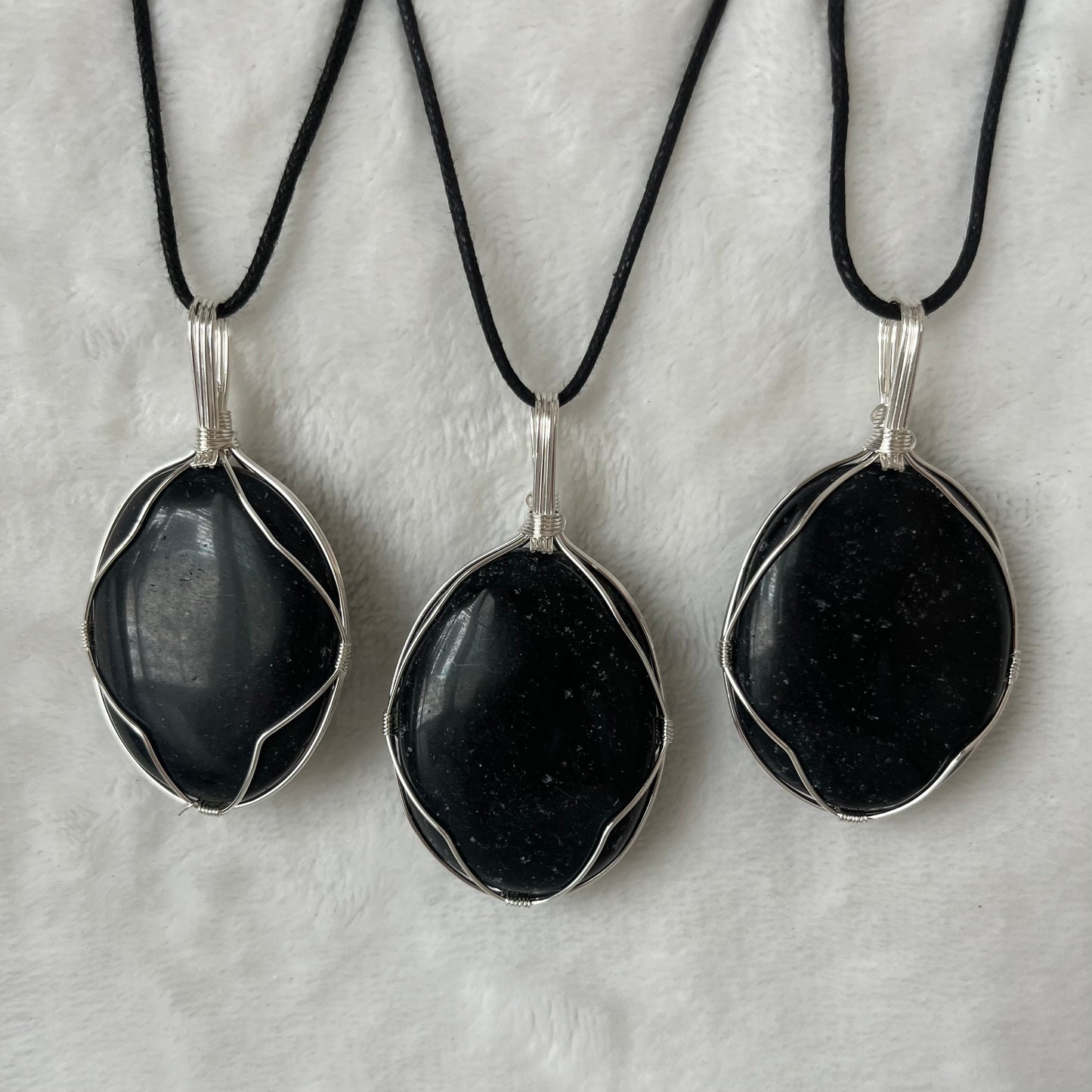 3 obsidian worry stones beautifully framed by silver wire and made into a pendant, with adjustable black cords.  obsidian crystal worry stones are approximately 1 1/2" long.