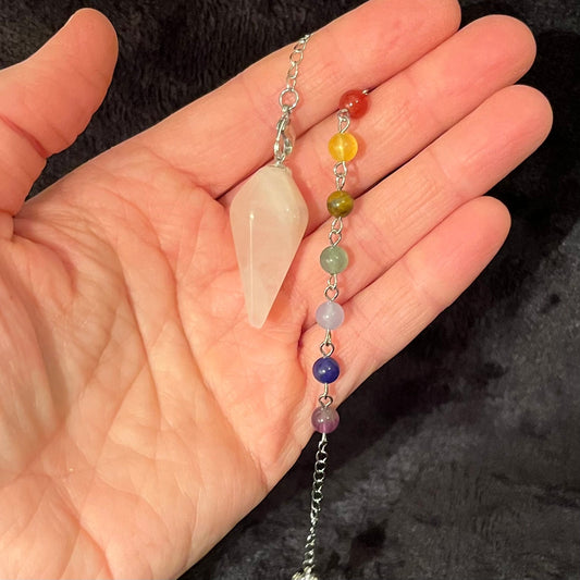 close up of a rose quartz pendulum attatched to a silver chain incuding chakra beads.