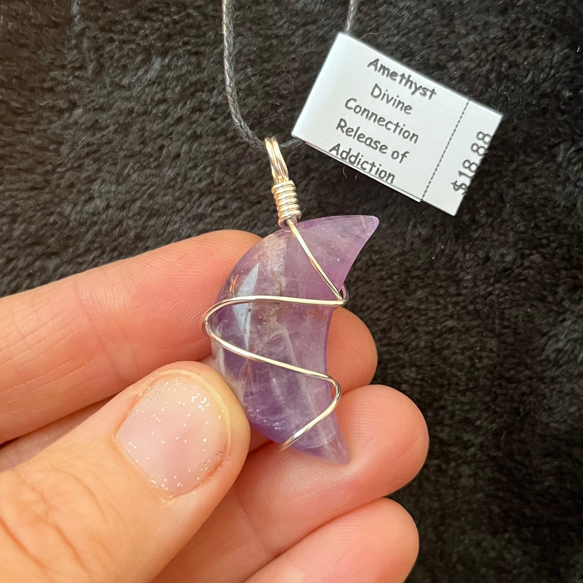 amethyst crescent moon, silver wire wrapped pendant attatched to a black adjustable cord displayed against a black background to enhance the beautiful purple tone interlaced with white 