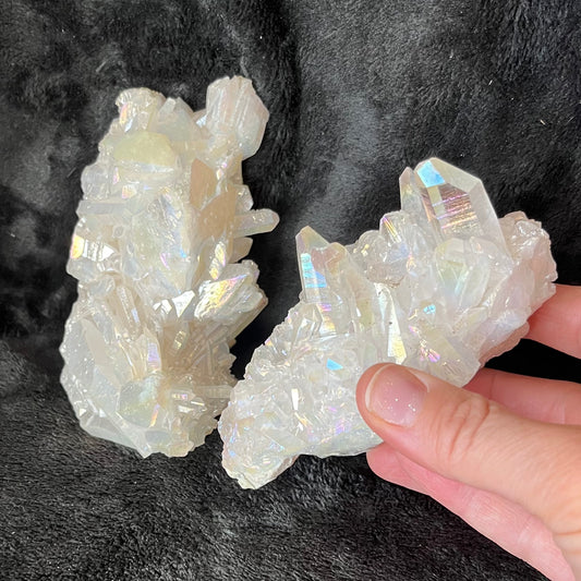 2 mesmerizing Angel Aura Quartz clusters featuring iridescent pastel hues, reflecting shades of pink, purple, and blue, with delicate crystal formations."